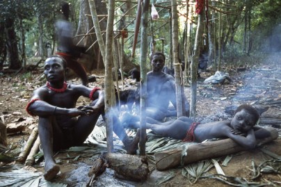 Members of a Jarawa community lie near a wood fire in their